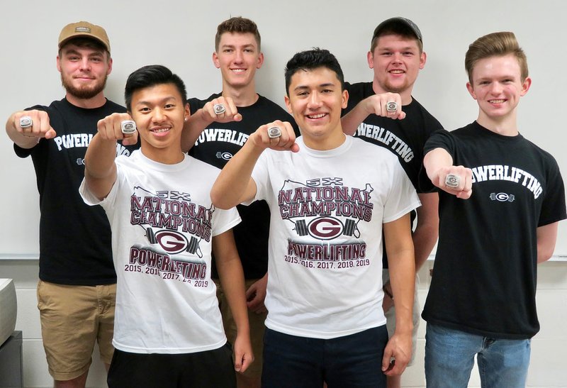 Westside Eagle Observer/RANDY MOLL Showing off their national championship powerlifting rings from the last season on Thursday (Aug. 1, 2019) are Gentry powerlifters Ethan Xiong (front, left), Jason Mendoza, Gavin Taylor (back, left), Mason West, Dylan Kilgore and Jackson Mcafee. Not pictured are Hunter Mills, Kerlose Ruzek, Coach Kaven Flesner and Coach Sean Seligman.