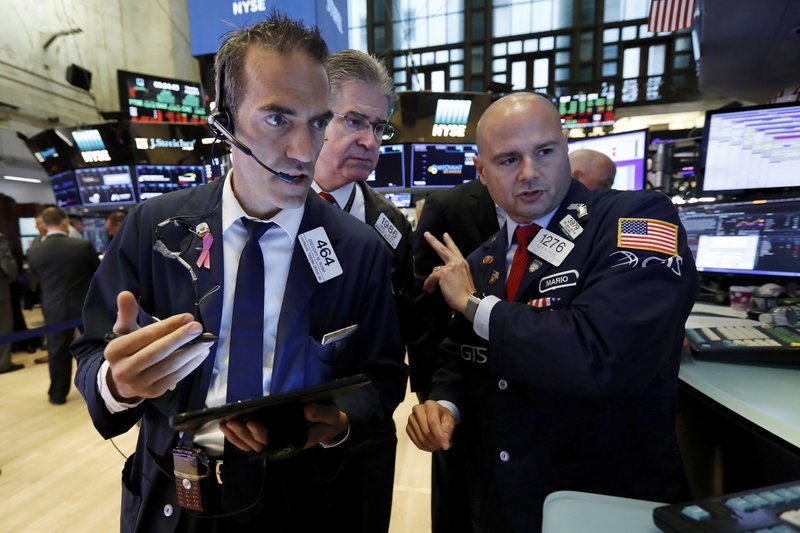 The Associated Press STOCKS RISING: Traders Gregory Rowe, left, and Daniel Kryger, center, work with specialist Mario Picone on the floor of the New York Stock Exchange, Tuesday. Stock markets turned higher on Tuesday as China stabilized its currency after allowing it to depreciate against the dollar in response to President Donald Trump's decision to put more tariffs on Chinese goods.