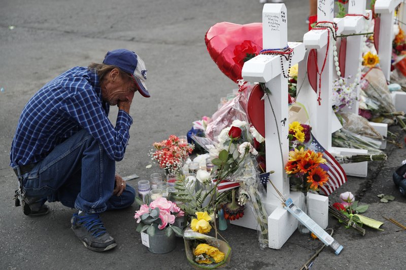 A man cries beside a cross at a makeshift memorial near the scene of a mass shooting at a shopping complex Tuesday, Aug. 6, 2019, in El Paso, Texas. The border city jolted by a weekend massacre at a Walmart absorbed more grief Monday as the death toll climbed and prepared for a visit from President Donald Trump over anger from El Paso residents and local Democratic leaders who say he isn't welcome and should stay away. (AP Photo/John Locher)