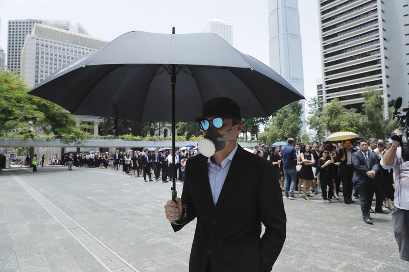 A man carries an umbrella and wears a face mask as lawyers gather for a protest march in Hong Kong, Wednesday, Aug. 7, 2019. (AP Photo/Kin Cheung)