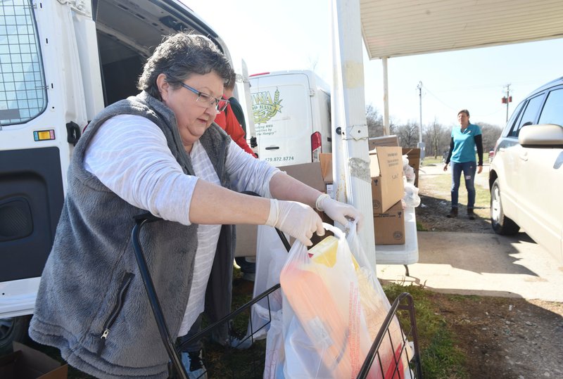 A volunteer helps distribute food March 26, 2019, during the Northwest Arkansas Food Bank's monthly visit to the Billy V. Hall Senior Activity Center in Gravette.