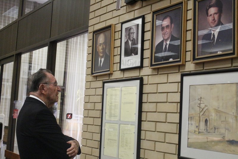 Celebration: Former National Bank of Commerce President James Cook examines a wall of history, including the minutes from the bank's first directors and photographs of the bank's past and present presidents, at Simmons Bank yesterday during a celebration commemorating 100 years in El Dorado for the bank. Simmons Bank was previously known as the National Bank of Commerce. Former and current employees and executives were also in attendance yesterday, with some traveling across the state to attend.
 Caitlan Butler/News-Times