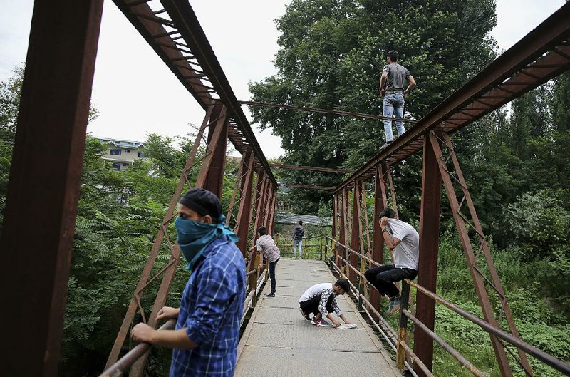 Kashmiri protesters monitor positions of Indian soldiers from a footbridge Friday in Srinagar, India. 