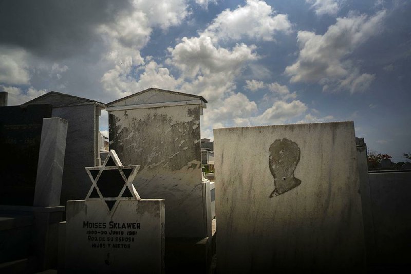 Tombs decorated with the Star of David, and one lacking the image of a person, stand in the Jewish cemetery in Guanabacoa, located in eastern Havana, Cuba. American Jews have contributed to the upkeep of some burial plots, but the cemetery as a whole was largely left to deteriorate. 