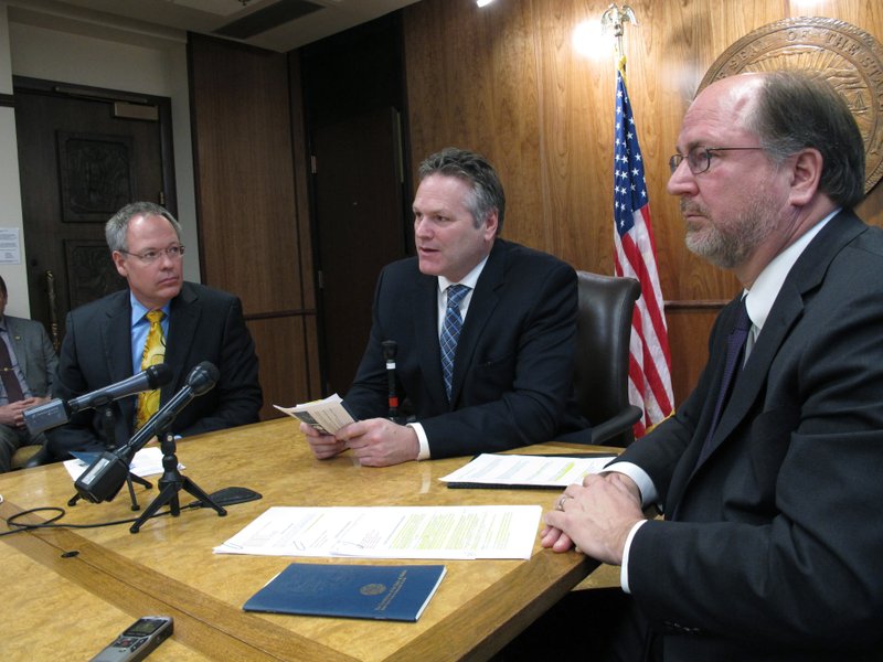 FILE - In this Jan. 30, 2019 file photo, Alaska Gov. Mike Dunleavy, center, speaks to reporters in Juneau, Alaska, with Revenue Commissioner Bruce Tangeman, left, and Attorney General Kevin Clarkson, right. For decades, Alaska has had an uneasy reliance on oil, building budgets around its volatile boom-or-bust nature. When times were rough, prices always seemed to rebound, forestalling a day of reckoning some believe may finally have come. The situation has politicians weighing changes to the annual dividend paid to residents from earnings of the state's oil-wealth fund, the Alaska Permanent Fund. (AP Photo/Becky Bohrer, File)