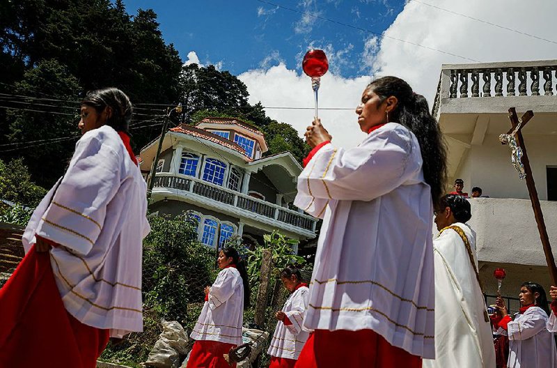 A church procession passes homes in Todos Santos, Guatemala, that were built in a grandiose style known as remittance architecture, funded with money townspeople earned in the United States. 