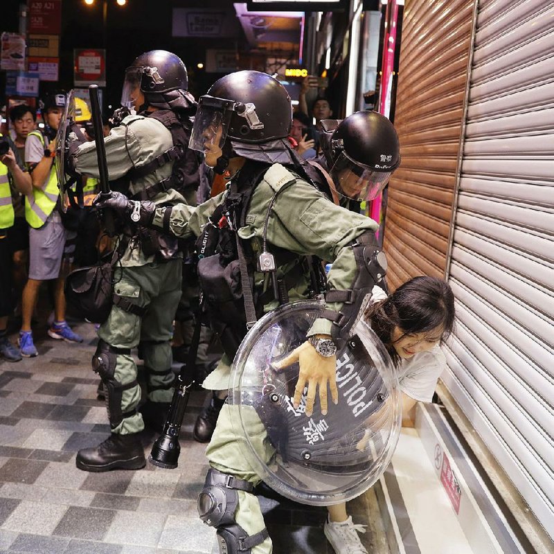 Police detain a woman Saturday during a protest in Hong Kong. The island is in its ninth week of protests over complaints that leaders in Hong Kong and mainland China are eroding the liberties of the semiautonomous territory. Officers on Saturday fired tear gas into crowds of demonstrators in two areas where the protesters had gathered in defiance of an official ban. 
