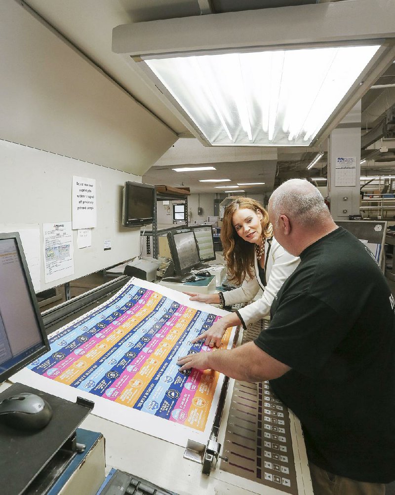 Kristi Dannelley, co-owner and president of Magna IV printing in Little Rock, works earlier this month with employee Blake Cross. 