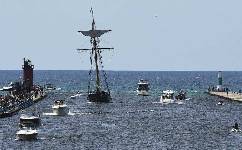 The Friends Good Will, a reproduction of a merchant ship that played a role in the War of 1812, sails past a lighthouse Saturday during the National Blueberry Festival in South Haven, Mich. 