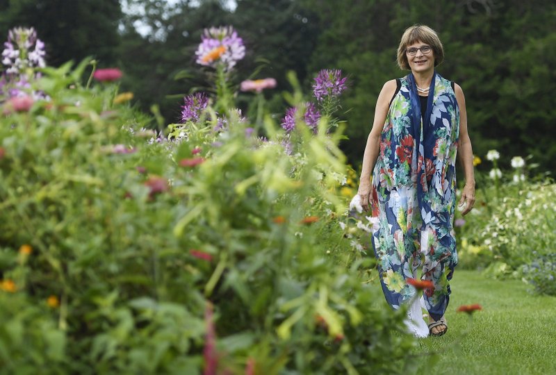 In this Thursday August 8, 2019 photo, Karen Breda poses for a photograph in a garden in West Hartford, Conn. Breda attended Woodstock to see a music concert that included the Who, Jimi Hendrix, Jefferson Airplane and Crosby, Stills, Nash &amp; Young in the lineup. (AP Photo/Jessica Hill)