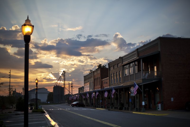 FILE-In this Sunday, Aug. 23, 2015 file photo, the sun rises behind Main Street in the hometown of former President Jimmy Carter in Plains, Ga. Former President Jimmy Carter's home county in rural south Georgia has been embroiled in a costly voting rights lawsuit that experts say could soon be replicated nationwide.(AP Photo/David Goldman)