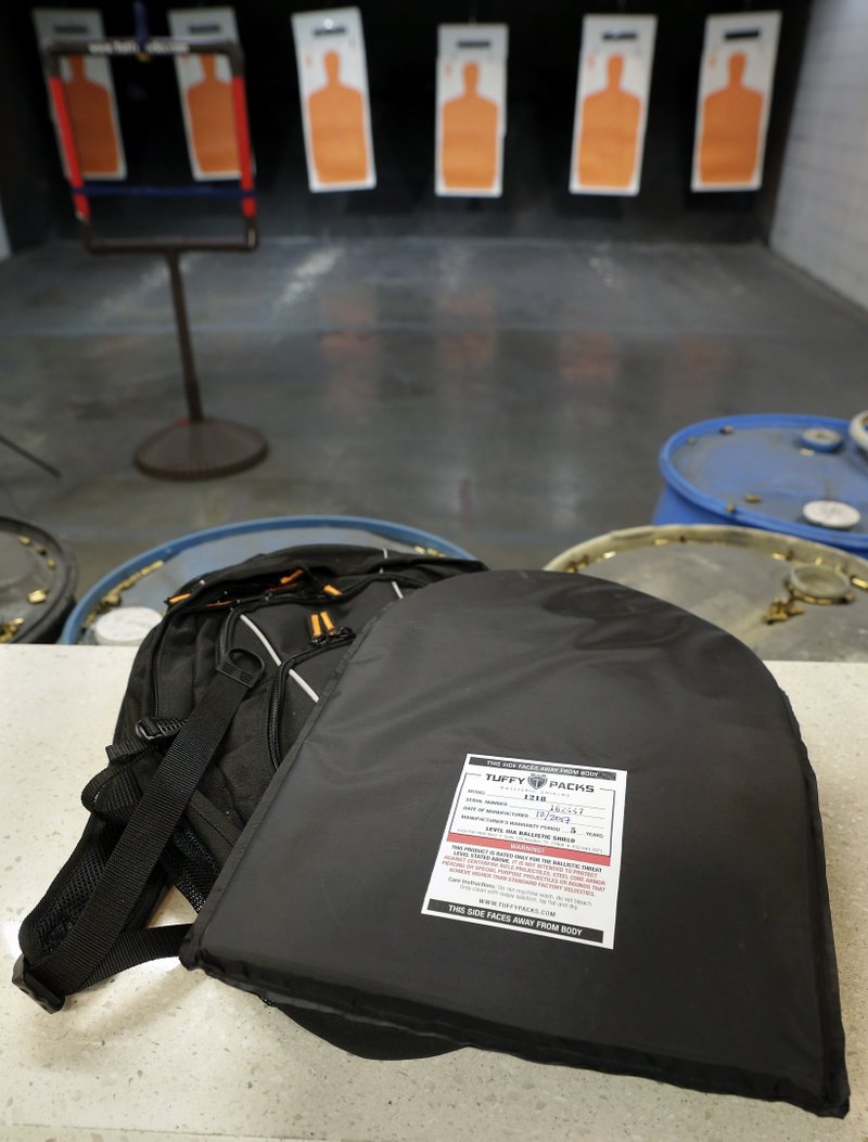 A TuffyPack ballistic shield sits on top of a backpack it will be inserted into before a shooting demonstration at the Shiloh Shooting Range, Friday, August 9, 2019, in Houston. The company produces some bullet-resistant backpacks but the bulk of the business is in removable ballistic shields that are inserted in backpacks. (AP Photo/Michael Wyke)