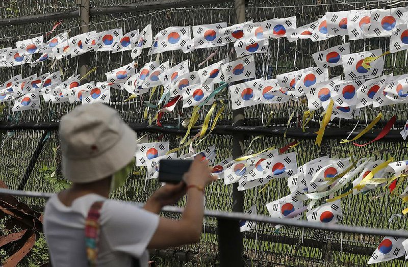 A visitor in Paju, South Korea, takes photos Sunday near a fence decorated with South Korean flags and ribbons with messages calling for the reunification of the two Koreas. The North Koreans have conducted five weapons tests since July 25, according to South Korea. 