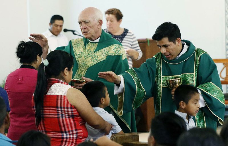 The Rev. Mike O’Brien (left) and Deacon Cesar Sanchez offer communion and blessings Sunday during Mass at Sacred Heart Catholic Church in Canton, Miss. Churches have offered comfort and aid after last week’s immigration raids, but some have also publicly denounced the government’s actions. 