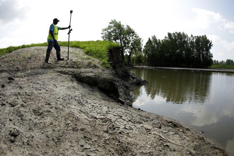 In this Tuesday, Aug. 6, 2019 photo, U.S. Army Corps of Engineers worker Ron Allen uses a GPS tool to survey the extent of damage where a levee failed along the Missouri River near Saline City, Mo. Efforts to fight rising waters may turn out to be only down payments on what is shaping up as a long-term battle against floods, which are forecast to become more frequent and destructive as global temperatures rise. (AP Photo/Charlie Riedel)