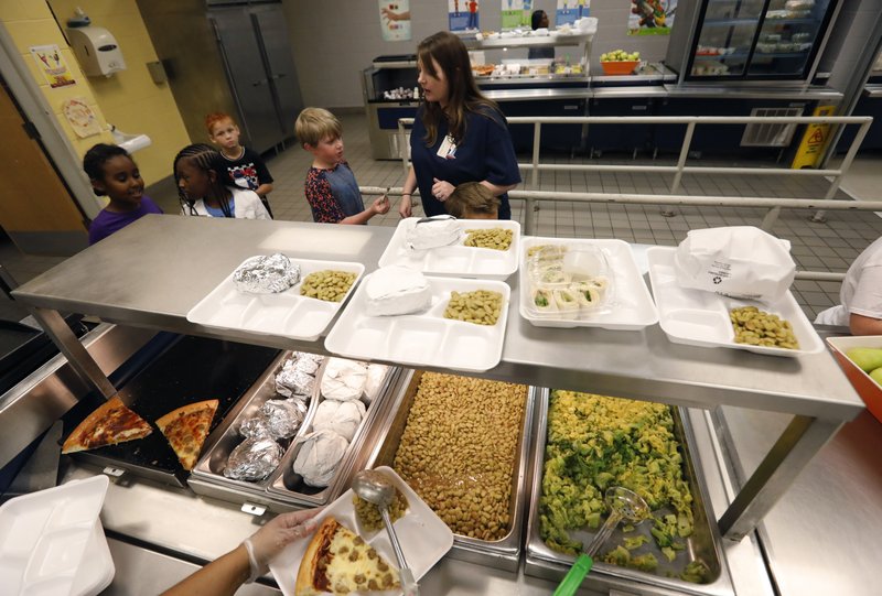 A teacher lines up the students for school-prepared lunches at Madison Crossing Elementary School in Canton, Miss., Friday, Aug. 9, 2019. Scott Clements, director of child nutrition at the Mississippi education department, said they've ordered two truckloads of trade mitigation pulled pork and four loads of kidney beans for use in their cafeterias. The products are coming from the U.S. Department of Agriculture, which is giving away the foods it&#x2019;s buying to help farmers hurt by trade negotiations. (AP Photo/Rogelio V. Solis)