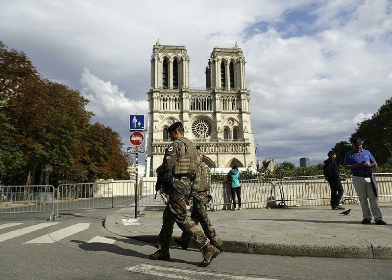 French soldiers work Monday to clear the area around Notre Dame Cathedral in Paris. Authorities said they plan to resume decontamination and cleanup work next week at the fire-dam- aged site, after new equipment and safety procedures ensure workers are not exposed to unsafe levels of lead. 