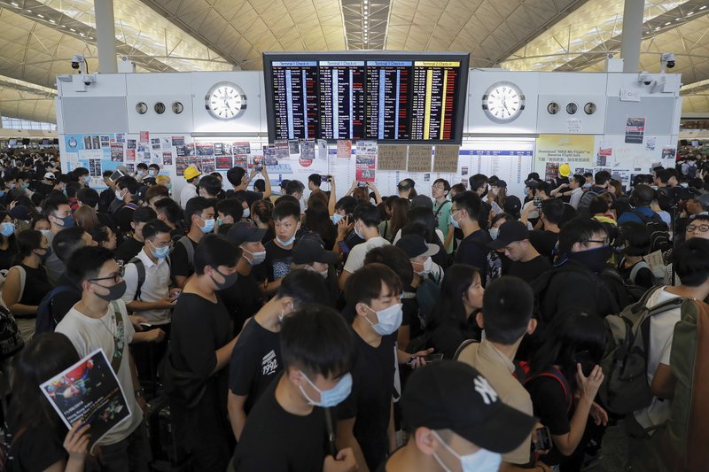 The Associated Press AIRPORT PROTEST: Protesters gather near a flights information board during a protest at the Hong Kong International Airport, Monday. One of the world's busiest airports canceled all flights after thousands of Hong Kong pro-democracy protesters crowded into the main terminal Monday afternoon. story.lead_photo.caption