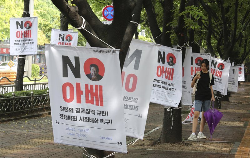 A South Korean woman takes pictures of banners with image of Japanese Prime Minister Shinzo Abe to denounce Japan's trade restrictions on South Korea on a street in Seoul, South Korea, Monday, Aug 12, 2019. South Korea said Monday that it has decided to remove Japan from a list of nations receiving preferential treatment in trade in what was seen as a countermeasure to Tokyo's recent decision to downgrade Seoul's trade status amid a diplomatic row. The sign reads &quot;No Abe.&quot; (AP Photo/Ahn Young-joon)