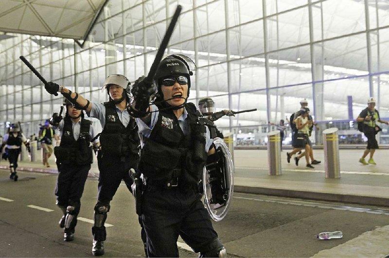 Hong Kong riot police officers move in against protesters Tuesday at the city’s airport. 
