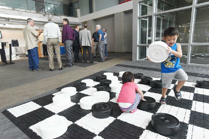 Children play with a jumbo checkers game Tuesday as guests gather for the announcement about new Allegiant Air flights between Northwest Arkansas Regional Airport and Phoenix. 