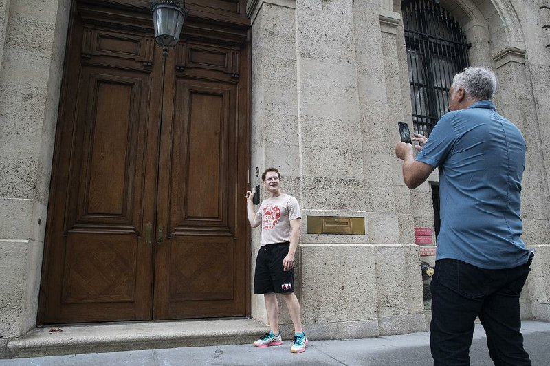 A man poses for a photo Tuesday outside Jeffrey Epstein’s townhouse in Manhattan’s Upper East Side. 