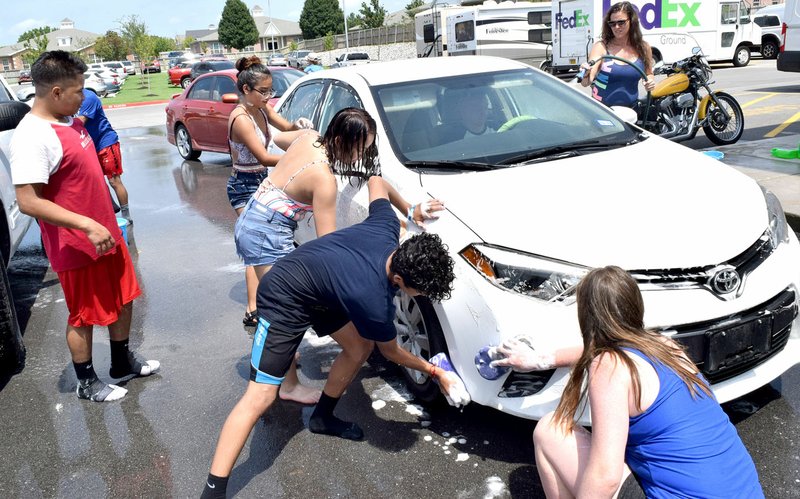 Westside Eagle Observer/MIKE ECKELS Members of the Decatur Cheer Team take on a dirty car Aug. 10 during the cheer team car wash at the McLarty Daniel Ford in Bentonville.