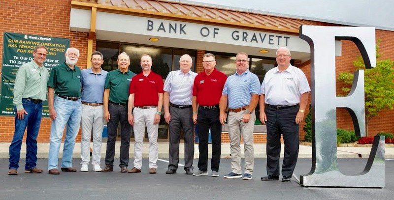 Photo by Beth Hall A group of Bank of Gravette and Legacy National Bank board members pose with the giant &quot;E&quot; which has been seen around Gravette recently. Pictured are Brian Glenn, Bank of Gravette president; board of directors members Loyd Swope, David Harris, and Steve Stafford; Patrick Swope, president and CEO, Legacy National Bank; Gary Jech, board of directors; Don Gibson, CEO, Emeritus Legacy National Bank; Matt Mawby, board of directors; and Gary George, chairman of the board.