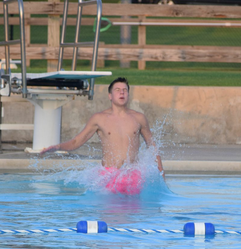 Westside Eagle Observer/MIKE ECKELS Sam Philpott enters the water after jumping off of the diving board at the Family Aquatic Center in Siloam Springs Aug. 9. Philpott was part of the Decatur Athletic Department swim night party.