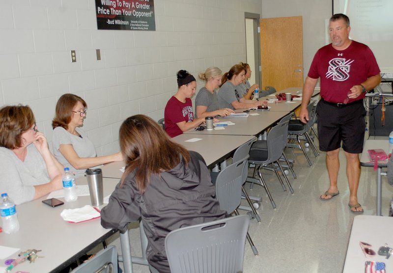 Graham Thomas/Herald-Leader Siloam Springs head coach Brandon Craig goes through the offense with moms of Panther football players Saturday at Panther Fieldhouse.
