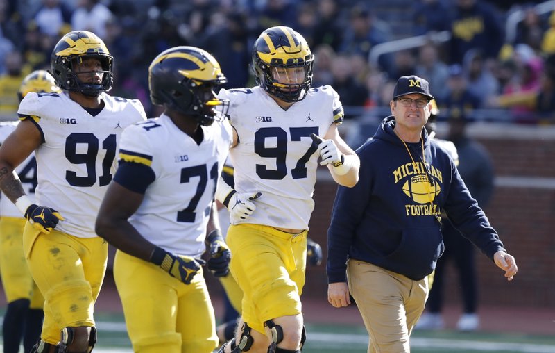 In an April 13, 2019, file photo, Michigan head coach Jim Harbaugh walks out with players during the team's annual spring NCAA college football game in Ann Arbor, Mich. (AP Photo/Carlos Osorio, File)