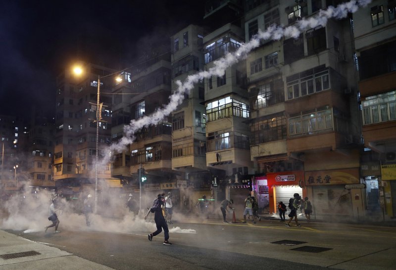 Protesters react to tear gas from Shum Shui Po police station in Hong Kong on Wednesday, Aug. 14, 2019. German Chancellor Angela Merkel is calling for a peaceful solution to the unrest in Hong Kong amid fears China could use force to quell pro-democracy protests.(AP Photo/Vincent Yu)

