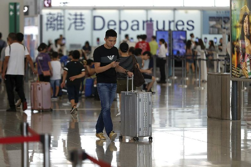 A traveler waits for his flight Wednesday morning in the departure area at Hong Kong’s airport, where service resumed after two days of delays, but some protesters remained in the terminal. 