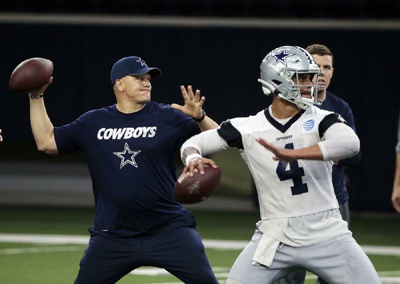 In this  Wednesday, May 22, 2019 file photo, Dallas Cowboys quarterbacks coach Jon Kitna throws the ball alongside Dak Prescott (4) during NFL football practice in Frisco, Texas. 