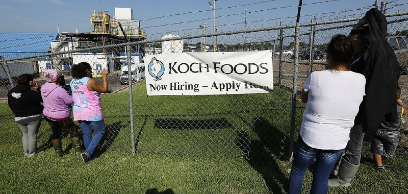 Friends, co-workers and family members watch as U.S. immigration officials raid a Koch Foods Inc. chicken processing plant in Morton, Miss., one of several such raids in Mississippi on Aug. 7. 