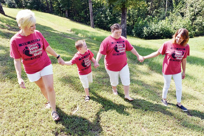 Holding hands and wearing their matching Clinton Down Syndrome Walk shirts are Randi Newland, from left, co-organizer; her son, Weston, 8; Sammy McJunkins, 20; and Sammy’s mother, Darla. The annual 1-mile walk is scheduled for 9 a.m. to noon Sept. 7. Proceeds from the walk will go to several nonprofit organizations.