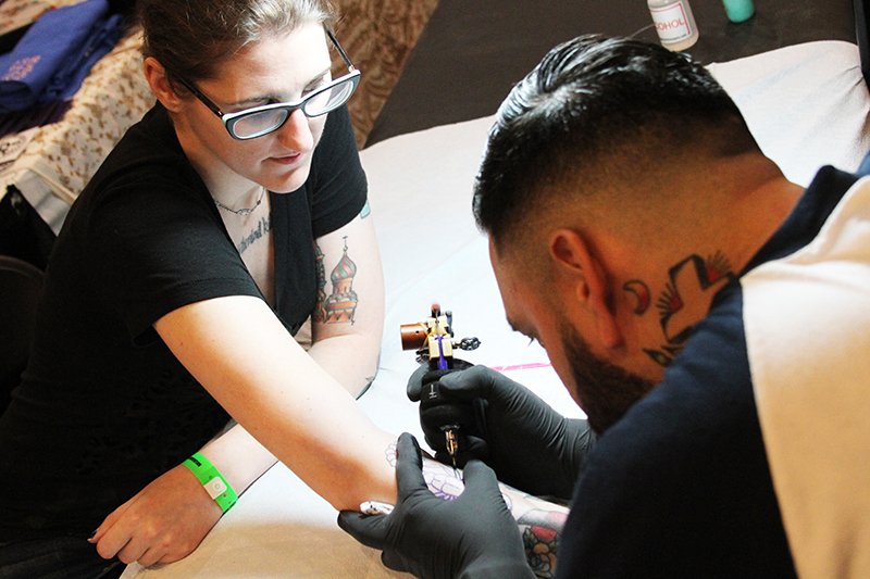 The Sentinel-Record/Tanner Newton INKING IN PROGRESS: Kayla Smith, of Little Rock, receives a tattoo from Miguel Arrue of Seventh Street Tattoo at the inaugural Arkansas Tattoo Fiesta Convention on Friday at the Arlington Resort Hotel & Spa.