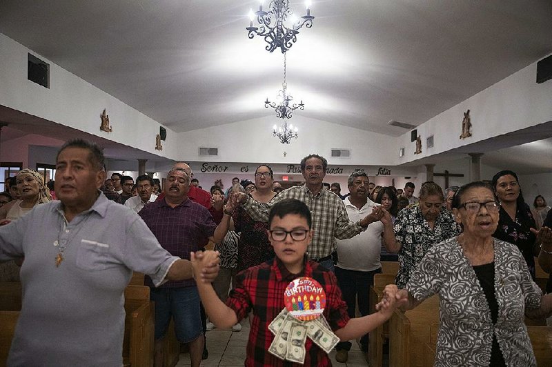 Parishioners hold hands in prayer during a Mass at El Buen Pastor Mission on the outskirts of El Paso, Texas, on Sunday, as they honor the victims and survivors of the city’s mass shooting. 
