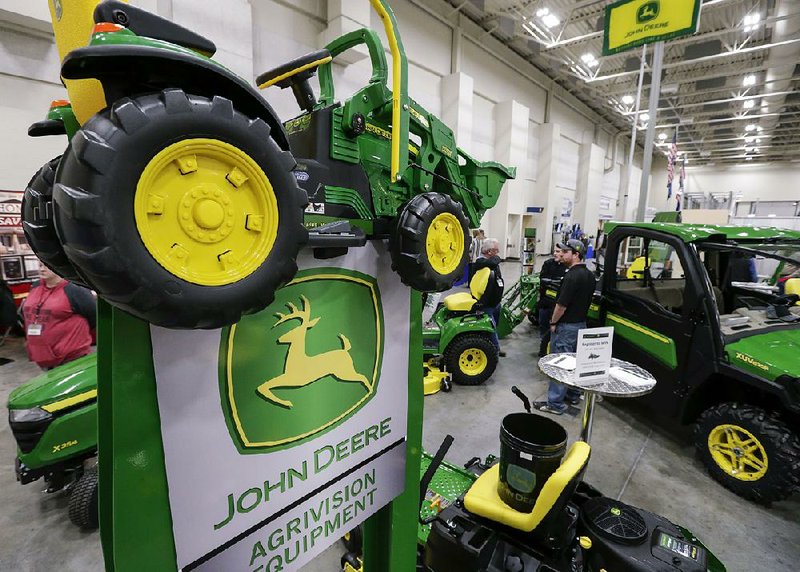 John Deere products, including a toy tractor, are displayed last year at a trade show in Council Bluffs, Iowa. Shares of Deere & Co. stocks rose 3.8% Friday after the company pledged to lower costs. 