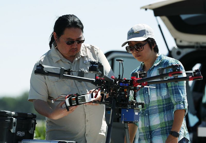 Engineering technician Kevin Yemoto (left) and Huihui Zhang work on the camera on a drone at a USDA research farm northeast of Greeley, Colo. 