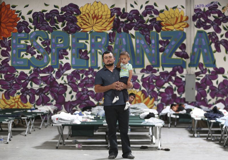  In this Wednesday, April 24, 2019 file photo, a Guatemalan man poses for a photo with his young son at the new Casa del Refugiado in east El Paso, Texas. Behind him is a full-wall mural which reads Esperanza, or hope. A federal appeals court ruling will allow the Trump administration to begin rejecting asylum at some parts of the U.S.- Mexico border for migrants who arrived after transiting through a third country. (Mark Lambie/The El Paso Times via AP, File)