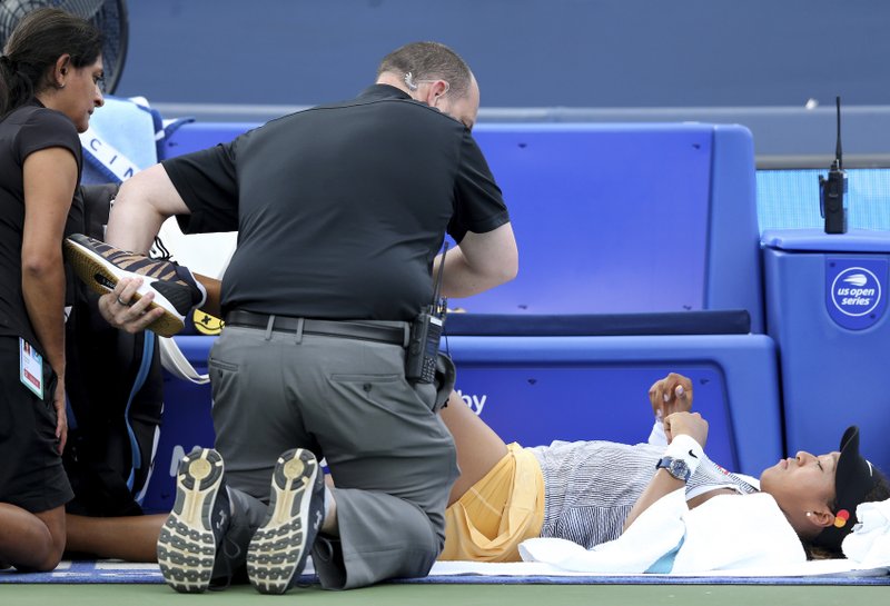 The Associated Press DOWN FOR THE COUNT: Trainers examine Naomi Osaka, of Japan, after she suffered a knee injury Friday in her match against Sofia Kenin, of the United States, in the quarterfinals of the Western &amp; Southern Open in Mason, Ohio. Osaka withdrew from the match.