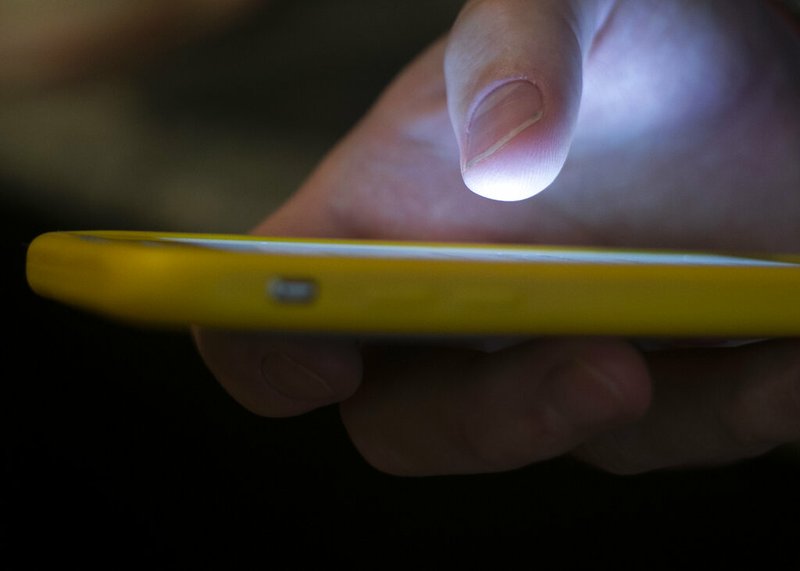 In this Sunday, Aug. 11, 2019, photo, a man uses a cell phone in New Orleans. With suicides on the rise, the government wants to make the national crisis hotline easier to reach. Once implemented, people will just need to dial 988 to seek help. Currently, National Suicide Prevention Lifeline uses a 10-digit number, 800-273-TALK (8255). Callers are routed to one of 163 crisis centers, where counselors answered 2.2 million calls last year. (AP Photo/Jenny Kane)