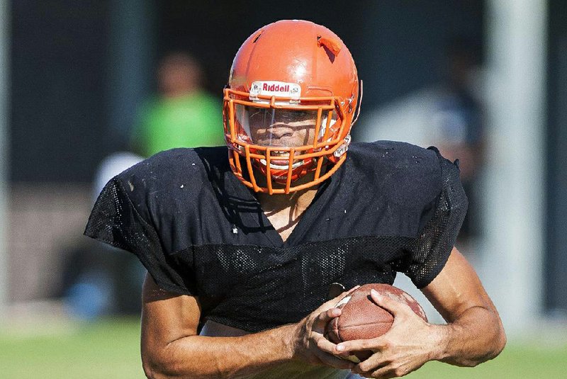 Little Rock Hall senior quarterback Braelon Adams carries the ball during the Warriors’ practice Friday. The Warriors and Coach Kipchoge VanHoose are optimistic after going 1-9 last season.