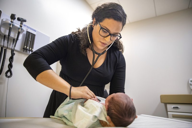 In this Tuesday, Aug. 13, 2019, photo, Dr. Jasmine Saavedra, a pediatrician at Esperanza Health Centers whose parents emigrated from Mexico in the 1980s, examines Alondra Marquez, a newborn baby in her clinic in Chicago. Doctors and public health experts warn of poor health outcomes and rising costs they say will come from sweeping changes that would deny green cards to many immigrants who use Medicaid, as well as food stamps and other forms of public assistance. Saavedra is convinced that if new Trump administration criteria were in effect for her parents three decades ago, she wouldn&#x2019;t have become a pediatrician. (AP Photo/Amr Alfiky)
