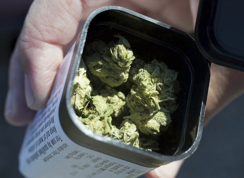 NWA Democrat-Gazette/CHARLIE KAIJO Brenna Hawkins of Bentonville holds a container of medical marijuana Thursday at The Source in Bentonville. She said she has replaced her prescribed pain medicine with a sativa she takes during the day and an indica before bed for pain management from fibromyalgia.