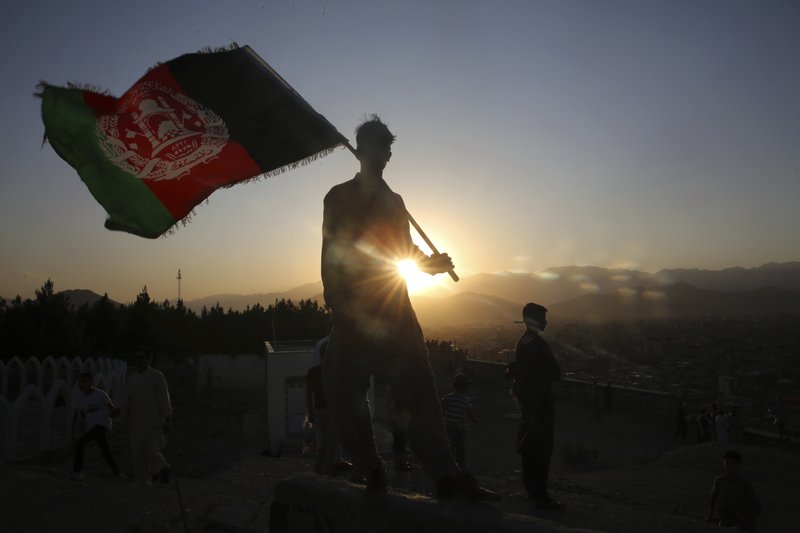 A man waves an Afghan flag during Independence Day celebrations in Kabul, Afghanistan, Monday, Aug. 19, 2019. Afghanistan's president is vowing to eliminate all safe havens of the Islamic State group as the country marks a subdued 100th Independence Day after a horrific wedding attack claimed by the local IS affiliate. (AP Photo/Rafiq Maqbool)

