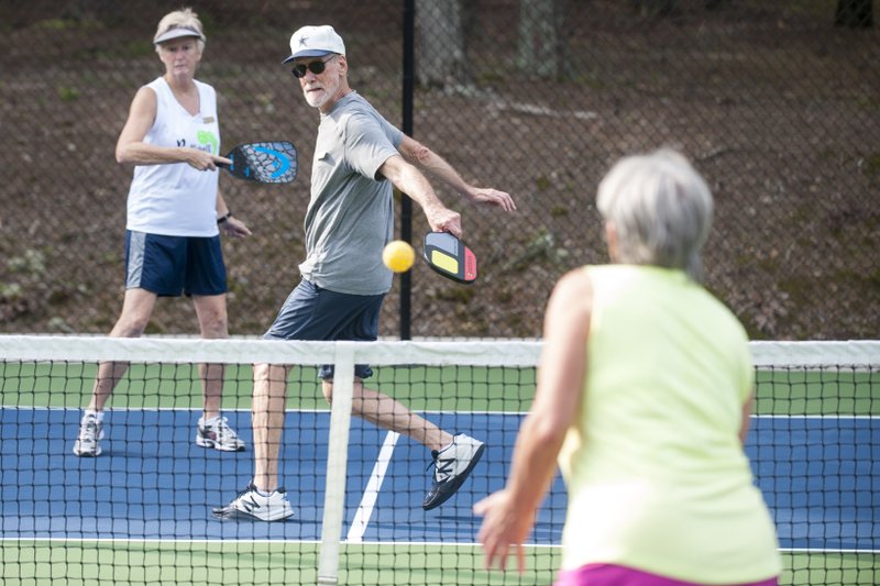 Mike Walters sends a backhand across the net to Diane Ransdell as Teresa Sage looks on during a pickleball game at Hot Springs Village. (Photo by Jeff Gammons, Arkansas Democrat-Gazette)