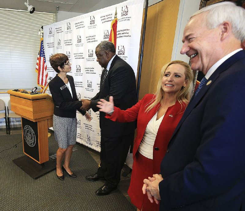 Theresa Beiner (from left), dean of the William H. Bowen School of Law at the University of Arkansas at Little Rock, shakes hands with Nate Todd, director of the state Department of Veterans Affairs, on Tuesday as Attorney General Leslie Rutledge talks with Gov. Asa Hutchinson after a news conference at the law school to announce the creation of a free legal clinic to help veterans get federal benefits. Video is available at arkansasonline.com/821aid 