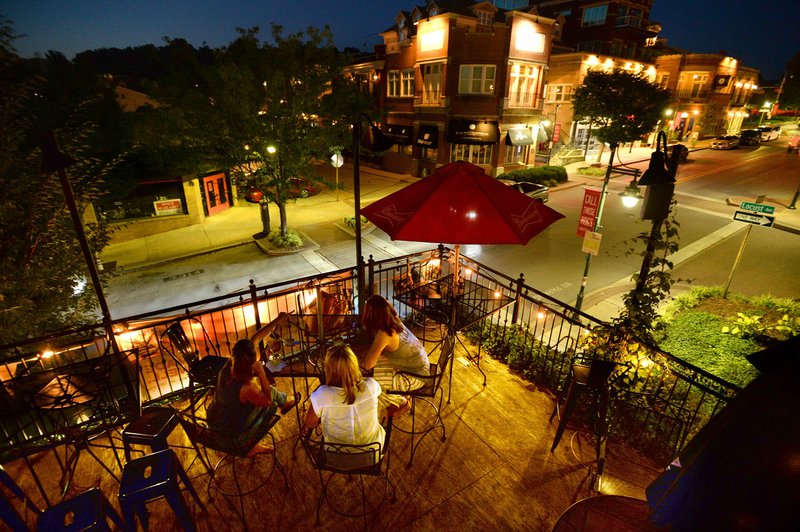 File photo/NWA Democrat-Gazette/ANDY SHUPE Amy Garrett (from left), Heather Hanes and Bridget Kachel sit together Thursday atop the Dickson Street Pub as cars pass on Dickson Street in Fayetteville. The City Council left on its first reading a measure to define the boundary and rules for its entertainment district, a new designation created under state law.